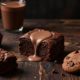 Assorted chocolate desserts and cocoa mugs arranged on a dark wooden table.