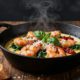 Creamy shrimp with spinach and sun-dried tomatoes in a skillet beside crusty bread.