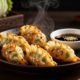 Golden cabbage dumplings with savory filling and soy-ginger dipping sauce on a dark plate.